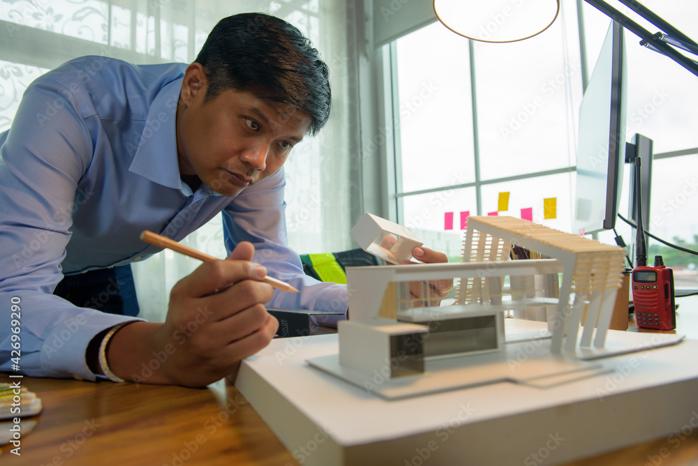 Poster architect-designer working with model of modern box house while thinking about concept of building a