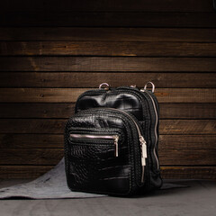 beautiful natural leather black bag on a wooden background with a leather belt