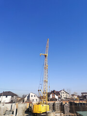 Fototapeta na wymiar Yellow crane on construction on blue sky background with copy space 