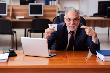 Old male employee playing cards at workplace