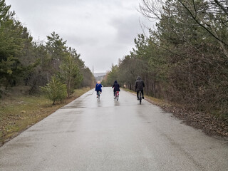 people cycling on the forest road in rainy day