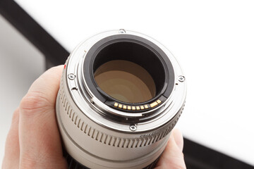 hand holding old white telephoto lens with visible bayonet and rear element