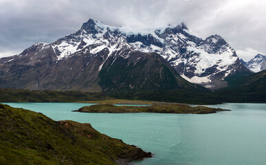 Fototapeta na wymiar Glacial coloured lake in the mountains of Patagonia with stormy sky with heavy clouds 