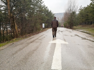 Man walking on asphalt forest road