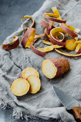 sweet potato tuber and round slices of raw yam on rough burlap gray napkin and potato peel on background. vertical food content, atmosphere of life, selective focus