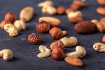 Assortment of various types of nuts on dark background. Cashew, hazelnuts, almonds and Brazil nuts close up. Healthy vegetarian snacks. Protein-containing food. Selective focus.