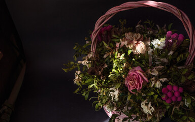 Wicker pink basket with dry flowers composition on a dark backdrop with copy space