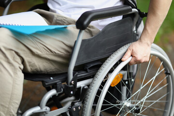 Man in wheelchair holds wheel with his hand