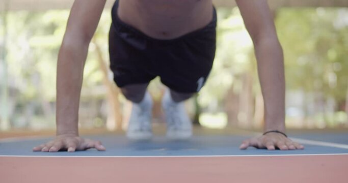 Shirtless Asian teenage man doing push-ups to exercise until he sweats.