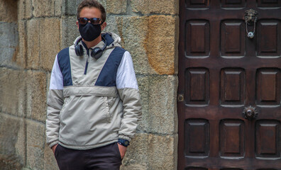 man through the monumental streets with medical mask and headphones in the new normal