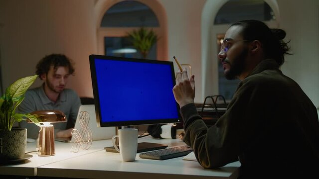 Guy of team thinks holding pencil at computer blue display