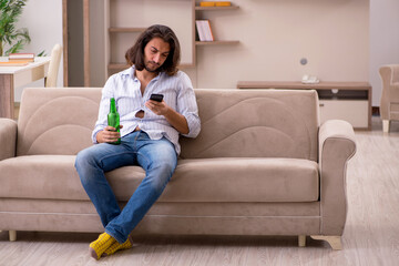 Young man drinking alcohol at home