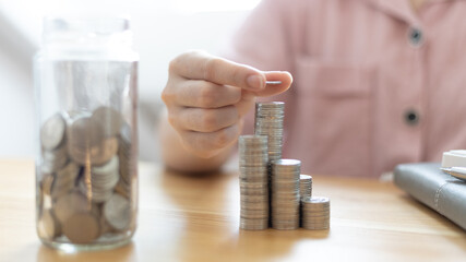 Woman's hands put the coins arranged in steps, Managing your finances or saving money for future use, Saving for investment, Saving money for business growth or long-term profitability.