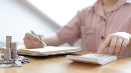 Dollar coins arranged in a slope graph, Blurred image of a businesswoman pressing a calculator, Take a notebook to record information, Saving money for business growth, Save money.