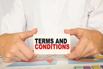 a man in the office holds a card with text TERMS AND CONDITIONS . business concept