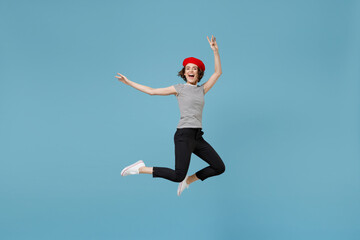 Full length young overjoyed fun excited woman 20s with short hairdo in french beret red hat striped t-shirt jump high with outstretched hands isolated on pastel blue color background studio portrait. - obrazy, fototapety, plakaty