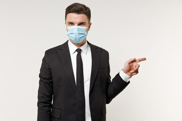 Young employee business corporate lawyer man in classic black suit tie face mask coronavirus covid-19 pandemic quarantine work in office point finger aside on workspace isolated on white background.