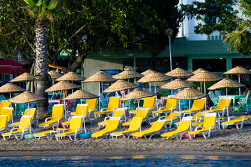Front landscape image of a sandy beach full of empty tanning beds 