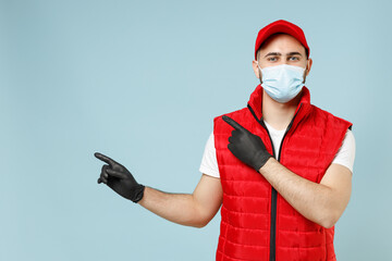 Delivery guy employee promoter man in red cap white t-shirt vest uniform sterile face mask gloves work courier service on lockdown coronavirus flu showing workspace isolated on pastel blue background.