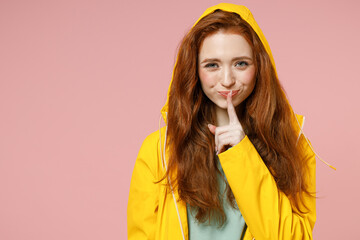 Redhead young secret woman in yellow waterproof raincoat outerwear hood say hush be quiet with...