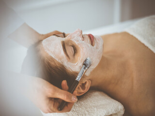 Beautiful brunette woman enjoying applying cosmetic mask with closed eyes comfortable and blissful....