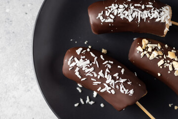 Frozen chocolate banana pops on dark plate. Healthy vegan dessert. close-up