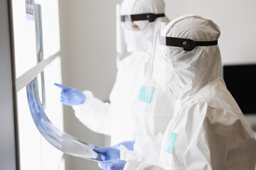 Two doctors in protective suits and masks examine an X-ray