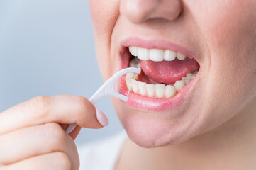 Caucasian woman brushing teeth with toothpick with dental floss on white background. - obrazy, fototapety, plakaty