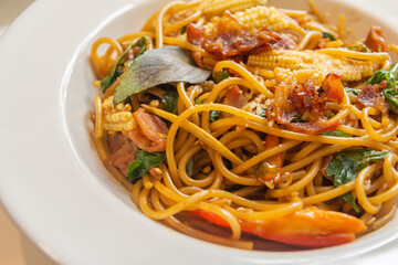 Spicy spaghetti with bacon and basil in the white dish.
