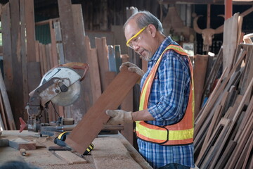 Old Asian male carpenter is working by aiming for the precision of the lumber. For accurate...