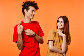 Obraz premium guy and girl in colorful t-shirts fun studio orange background