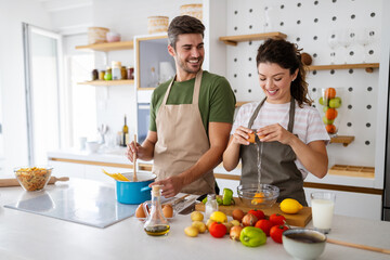 Happy young couple preparing food in kitchen at home
