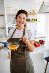 Happy woman making healthy food standing smiling in kitchen preparing food