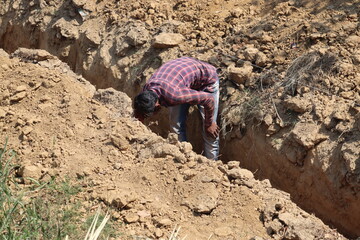 New Delhi, Delhi India- April 07 2021: A labor is involved in digging pits to form a trench or canal for irrigation and construction work. 