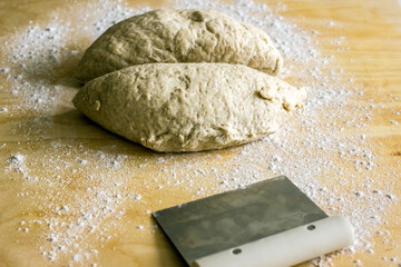 Rye dough for baking bread and knife for cutting dough on wooden background, close-up. Authentic...