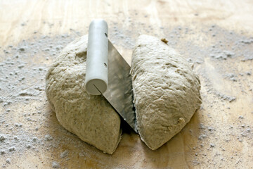 Rye dough for baking bread and knife for cutting dough on wooden background, close-up. Authentic...