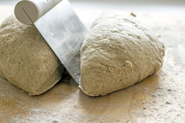 Rye dough for baking bread and knife for cutting dough on wooden background, close-up. Authentic hobby home baking