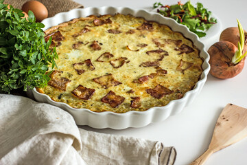 French onion pie with bacon in a baking dish, copy space. Authentic hobby homemade cakes, jellied pie with onions