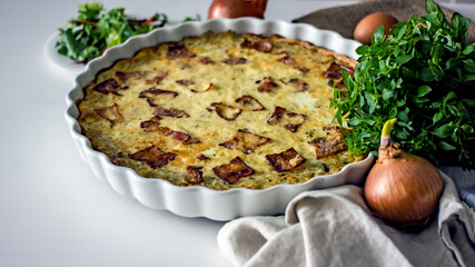 French onion pie with bacon in a baking dish, copy space. Authentic hobby homemade cakes, jellied pie with onions