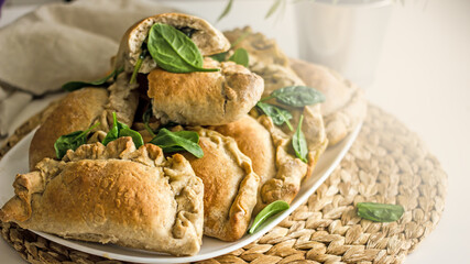 Homemade pies with spinach in a plate close-up. Authentic homemade hobby baked goods. Delicious rye flour pies with vegetable filling