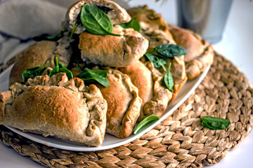 Homemade pies with spinach in a plate close-up. Authentic homemade hobby baked goods. Delicious rye flour pies with vegetable filling