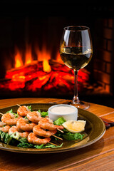 Fried prawns on skewers with basil, lemon and olives on old wooden background