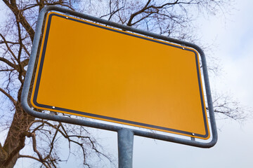 Gelbes Schild ohne Inhalt vor einem Baum im Winter.