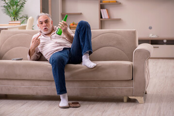 Obraz premium Old man drinking alcohol at home