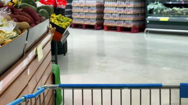 Slow motion scene of a person is pushing a shopping cart to buy vegetables and food to cook in the department store.