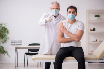 Obraz premium Young male patient visiting old male doctor in vaccination conce