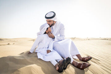 Naklejka premium Arabian man and son playing in the desert