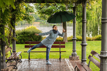 A girl sitting with an umbrella in the spring rain	
