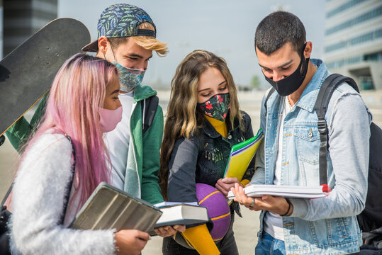 Multiethnic group of friends wearing coronavirus face masks meeting outdoors