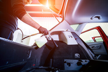 Naklejka premium A car service worker cleans interiror with a special foam generator